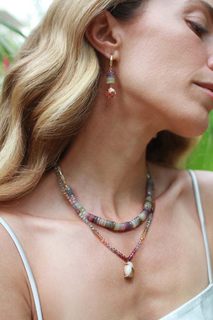 A magical treasure from nature, this necklace highlights a pear-shaped boulder Mexican opal, with a captivating display of green, yellow, and orange fire glowing at its center. Strung on silk thread, the opal is complemented by a vibrant array of multicolor Songea sapphires, adding warmth and vibrancy. A unique piece with an organic feel.&nbsp;