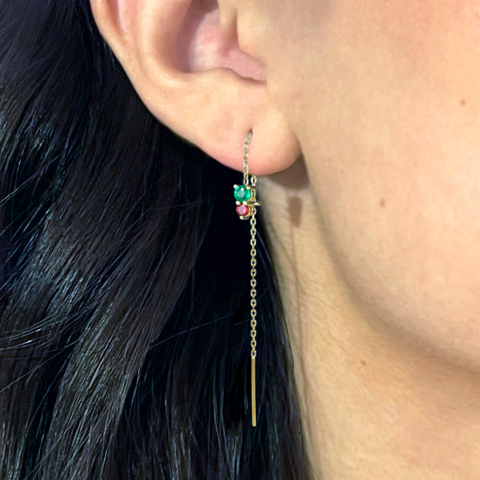 A lively emerald and ruby, beautifully contrasted, dangle at the end of a sparkling gold chain.