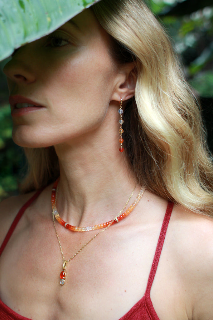 A vivid fire opal paired with a mystic moonstone forms a luminous charm, suspended from a sparkly cable chain. The charm is connected by a hinged bail accented with diamonds, adding a touch of brilliance to this radiant, ethereal piece.