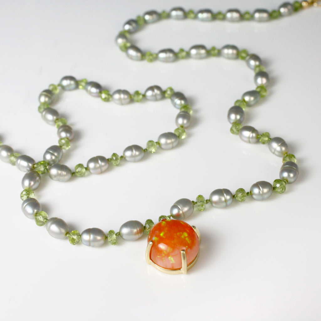 A vibrant Mexican opal radiates with lime-green fire, beautifully complemented by mint pearls and sparkling peridots—delicately knotted on silk thread.