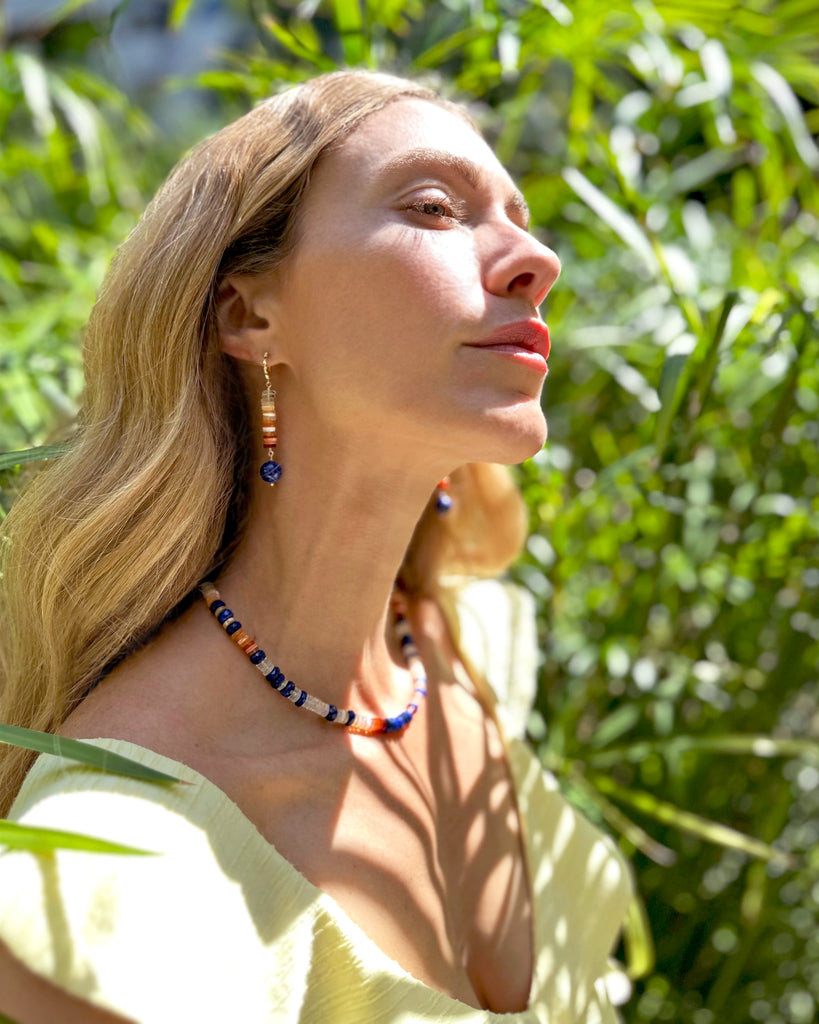 Inspired by the sun—the Aztec symbol of the god&nbsp;Tonatiuh—these bold dangle earrings feature heishi-cut ombré opals that flow in a radiant gradient from clear to fiery orange-red. Anchoring the piece is a round-cut, vibrant lapis lazuli stone. Daring, unique, and full of light.