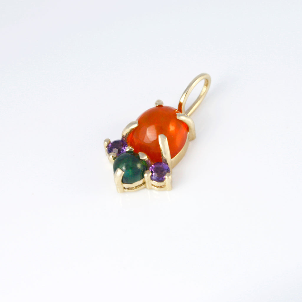 Vibrant Mexican orange crystal opal alongside green tourmaline and amethyst set in a simple yet striking 14k gold charm. Contrasting and lively colors.