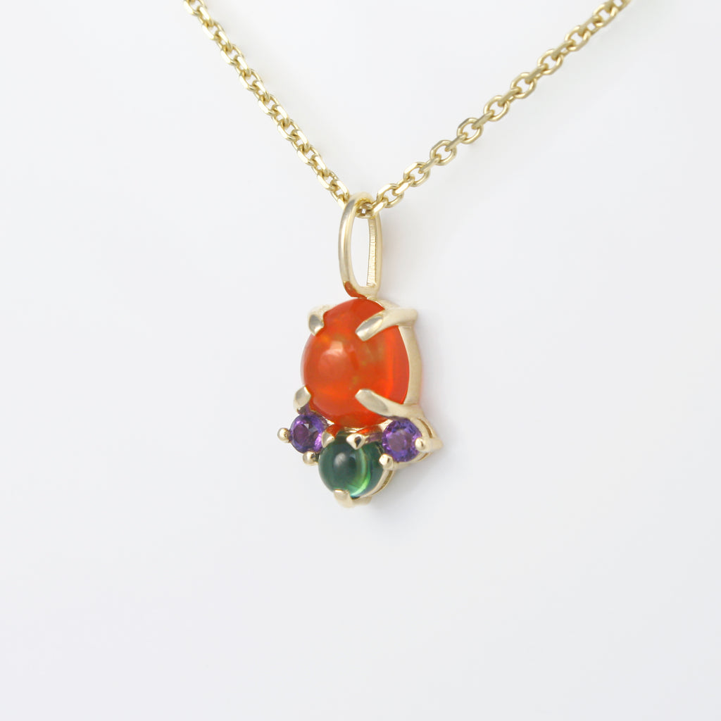 Vibrant Mexican orange crystal opal alongside green tourmaline and amethyst set in a simple yet striking 14k gold charm. Contrasting and lively colors.