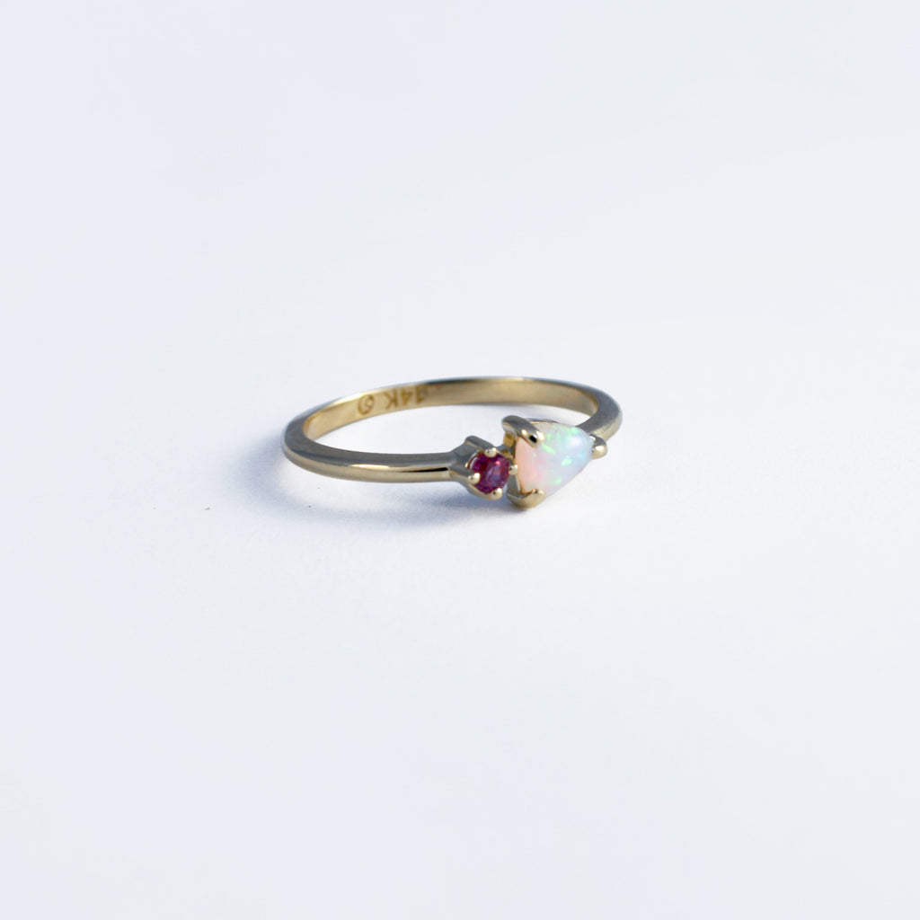 Dainty and dreamy 14k gold ring featuring a trilliant cut cabochon Mexican white opal paired together with a ruby. 