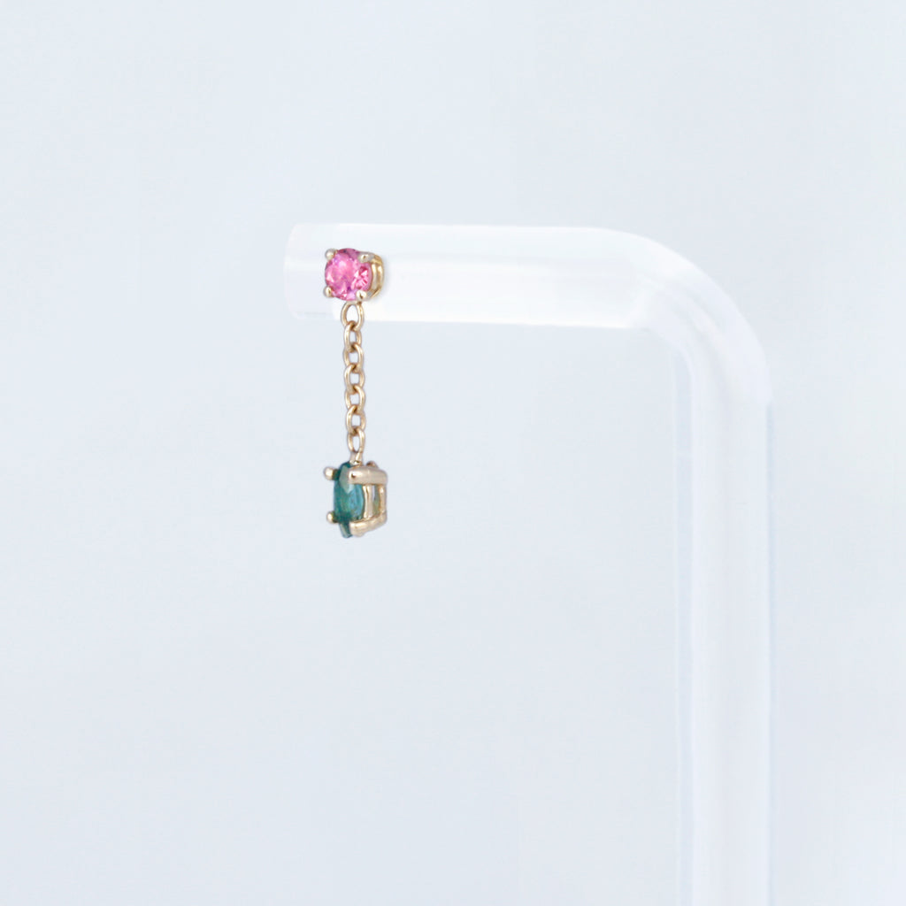 Delicate and femme earring featuring a vibrant green tourmaline anchored by a chain to a pink tourmaline. 