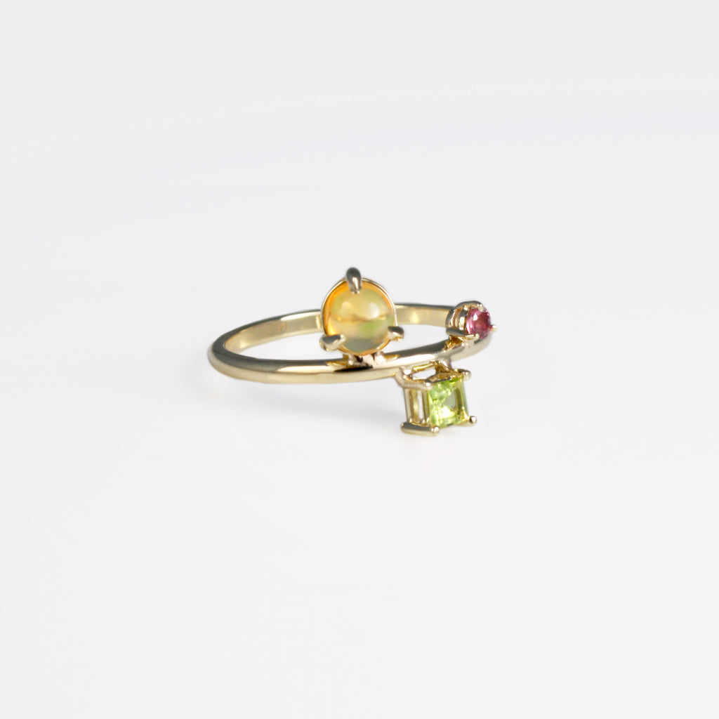 Designed for everyday use in mind, this 14k gold piece features a round cabochon Mexican orange crystal opal with green fire alongside a square faceted peridot and a round faceted ruby.