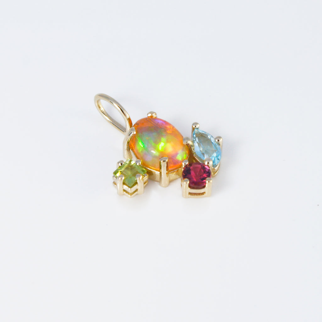 Striking Mexican crystal multicolor opal set in 14k gold charm alongside sky blue topaz, peridot and tourmaline.