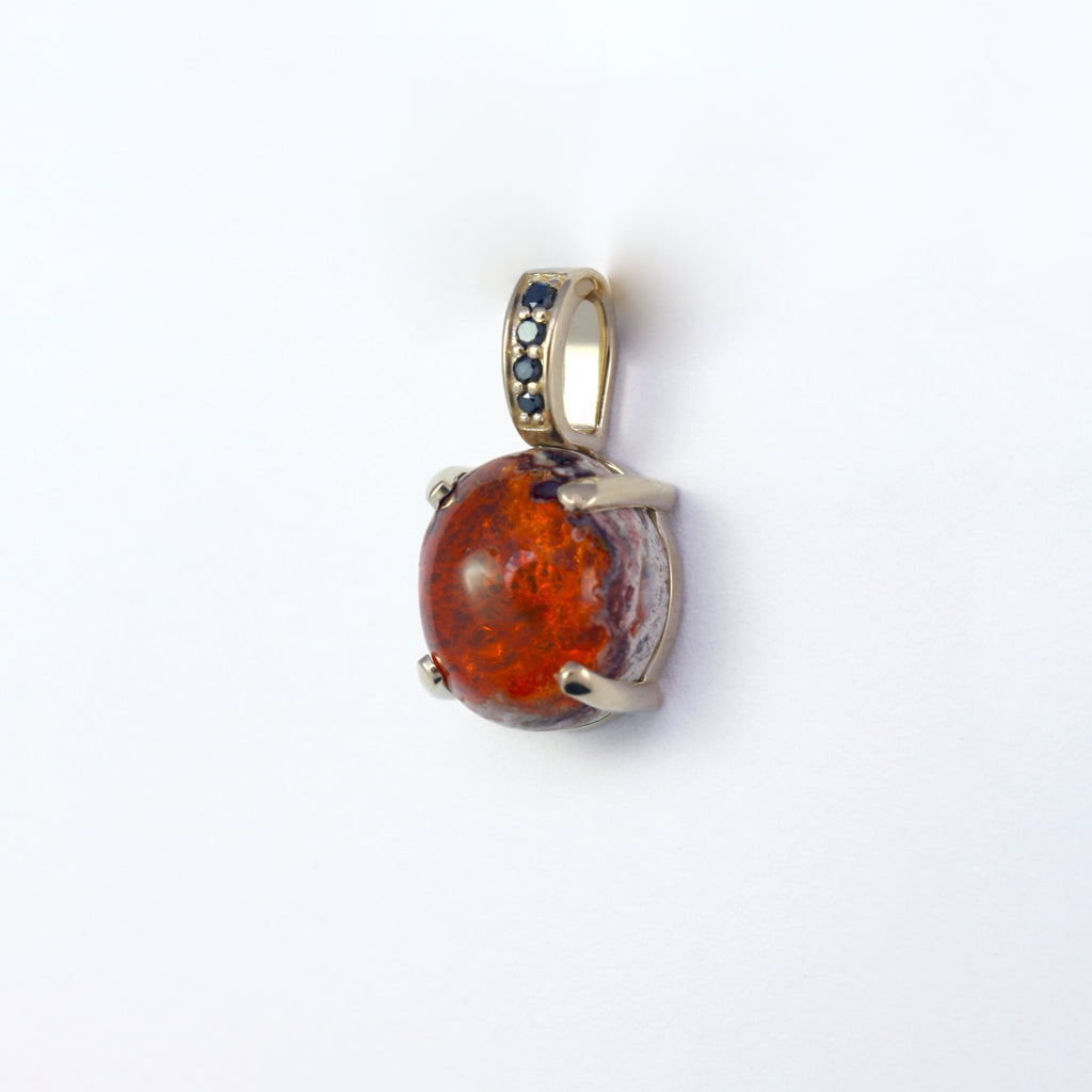 Bold and eye-catching Mexican boulder fire opal accented by black diamonds graduating in size set in 14k yellow gold.