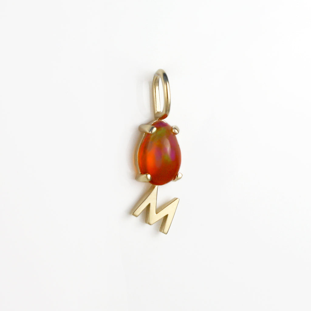 This 14k gold charm has a Mexican orange crystal opal alongside an M initial.