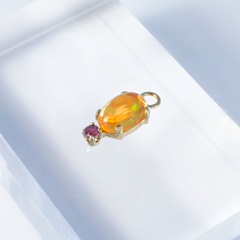 Mexican orange crystal opal set in 14k gold alongside a ruby.