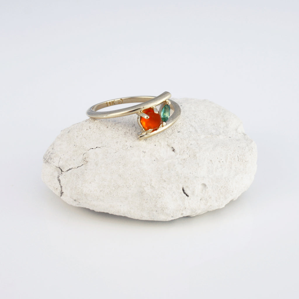 A vibrant Mexican orange crystal opal beautifully contrasted by a lively green tourmaline in an unexpected minimalist setting.