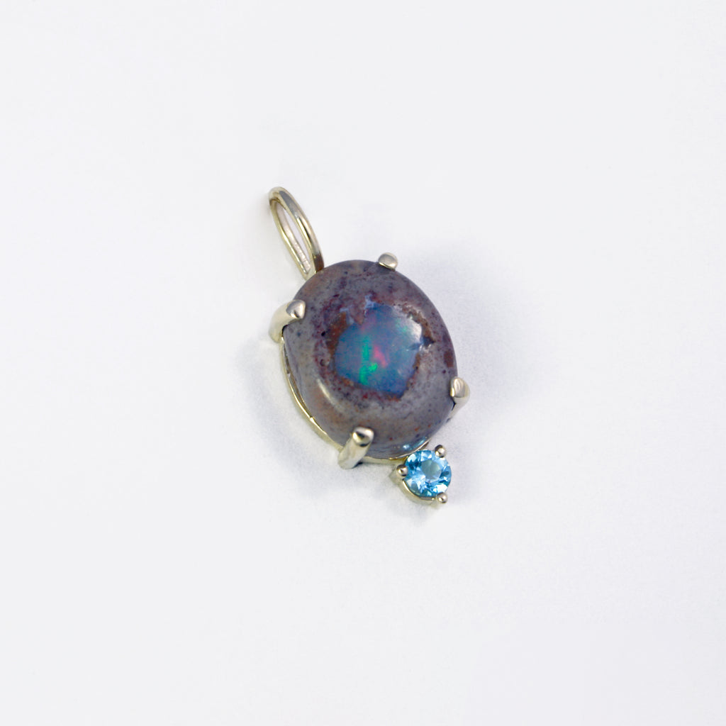 This simple charm features a unique Mexican blue boulder crystal opal and a sky blue topaz. Raw and sophisticated, the perfect statement. 