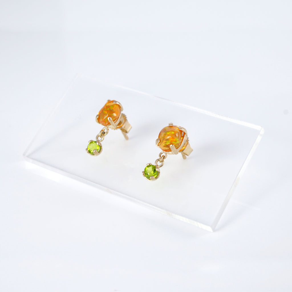 Gold earrings featuring free-form orange crystal opals linked by a chain to a vibrant peridot.