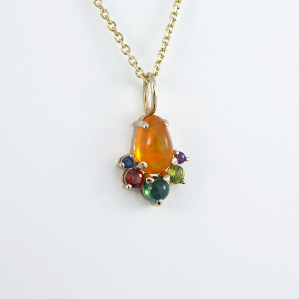 This vibrant charm features a stunning Mexican orange crystal opal beautifully contrasted by a tourmaline, garnet, sapphire, peridot and amethyst set in 14k gold.