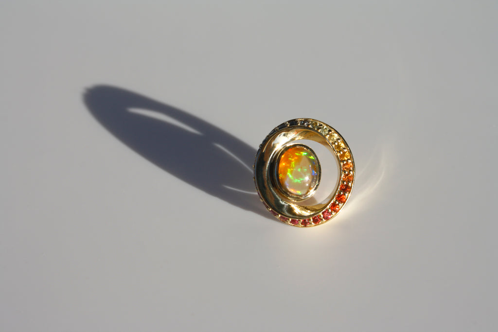 Mexican orange crystal opal with green-yellow fire suspended in a 14k gold twisted ring of multicolored sapphires.