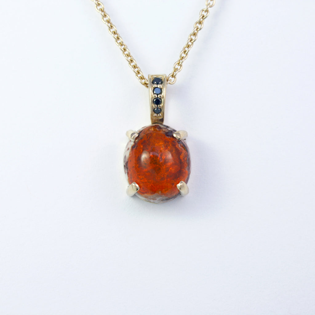 Bold and eye-catching Mexican boulder fire opal accented by black diamonds graduating in size set in 14k yellow gold.